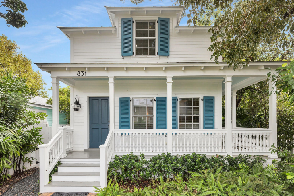 White house with teal shutters and porch.